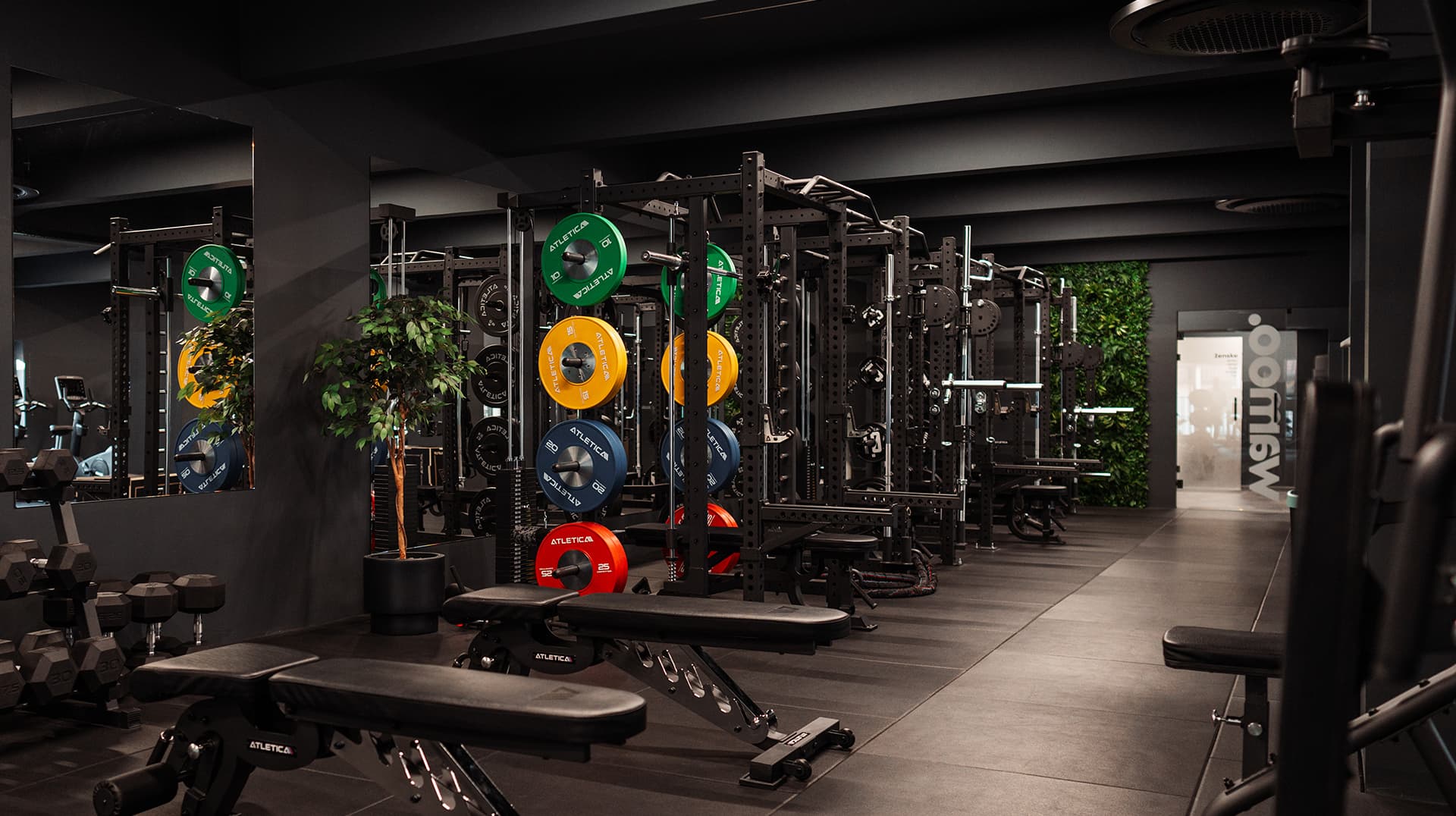 Fitnes prostor Wamoo z utežmi, napravami za moč in temnim premium ambientom